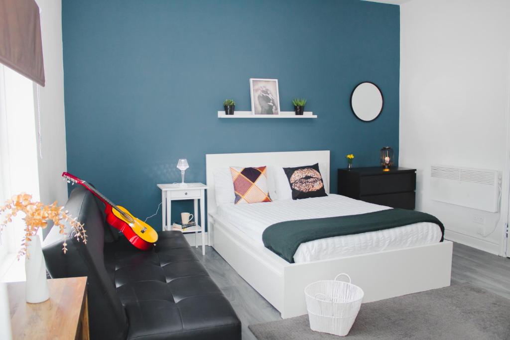 ein Schlafzimmer mit einem Bett und einer blauen Wand in der Unterkunft All-Inclusive Living: Modern Studio in Liverpool