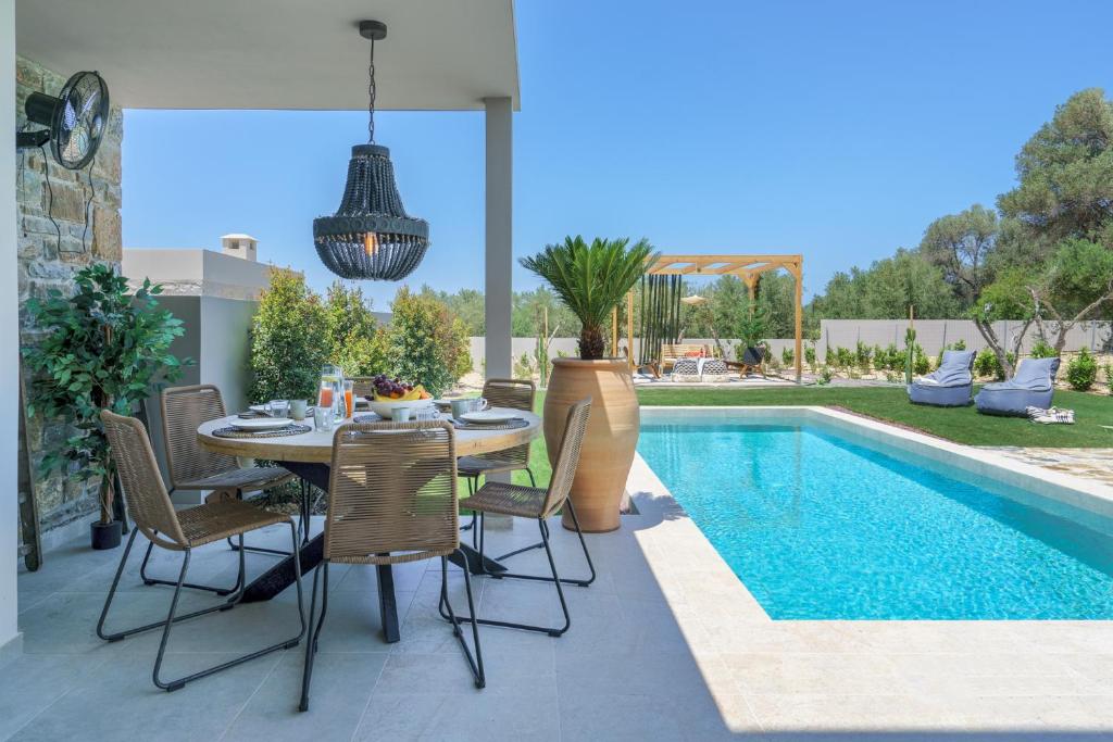 un patio con mesa y sillas junto a una piscina en Modern Family Villa Leba with Private Pool & BBQ, en Agios Dimitrios
