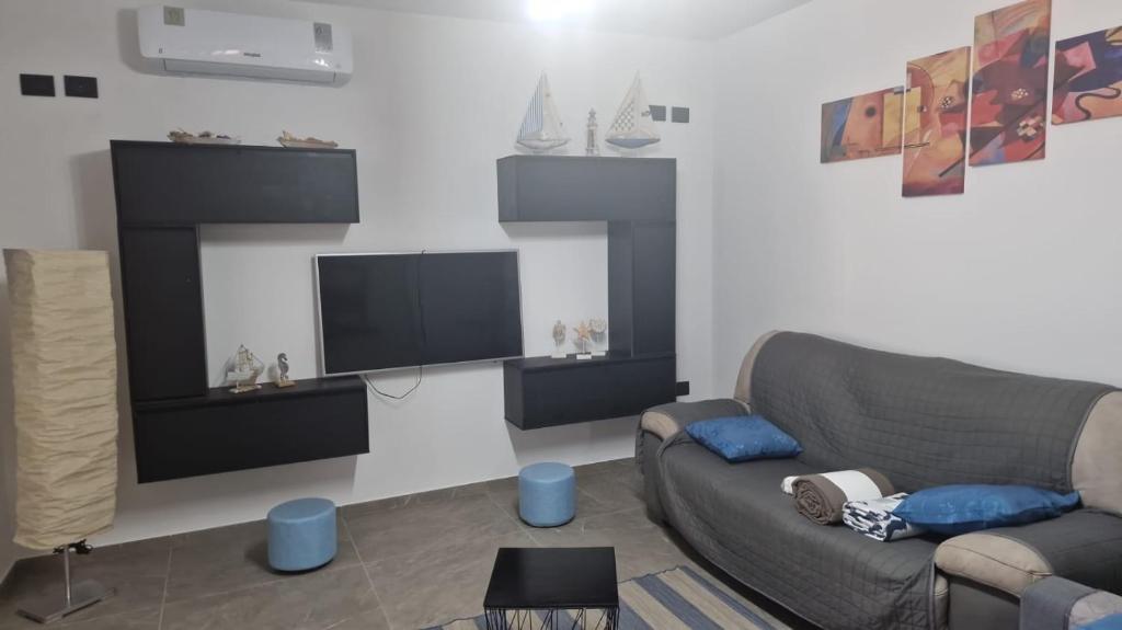 sala de estar con sofá y TV de pantalla plana en Orchidea Casa Vacanza, en Castro di Lecce