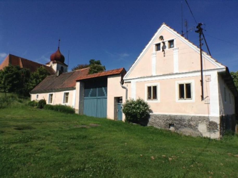 uma casa branca numa colina relvada com uma igreja em Návrat do starých časů, ubytování květen - září em Slabetz