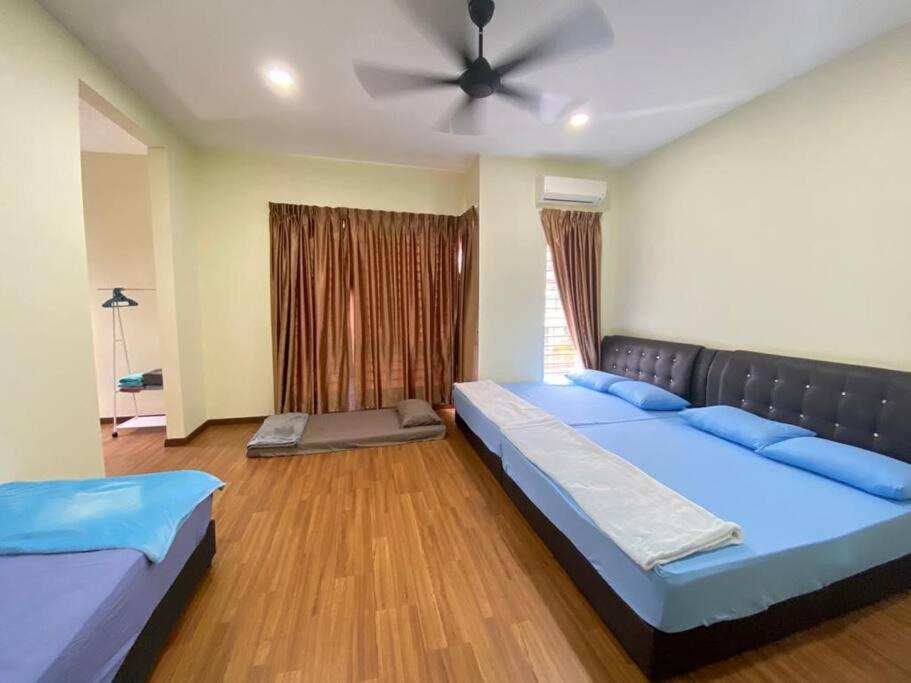 una camera da letto con due letti e un ventilatore a soffitto di Patience Homestay Kuala Selangor a Kuala Selangor