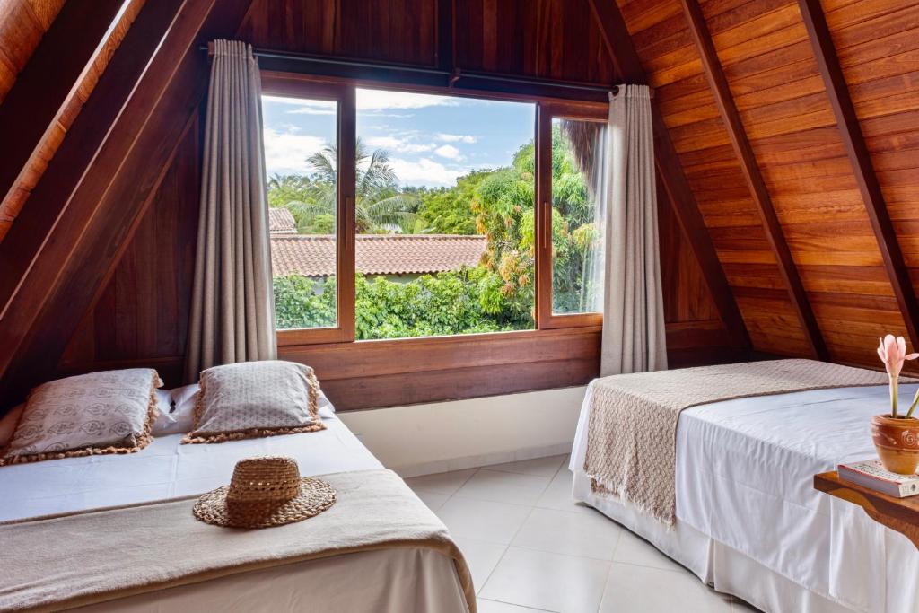 two beds in a room with a window at Aldeia dos Corais - Taipu de Fora in Barra Grande