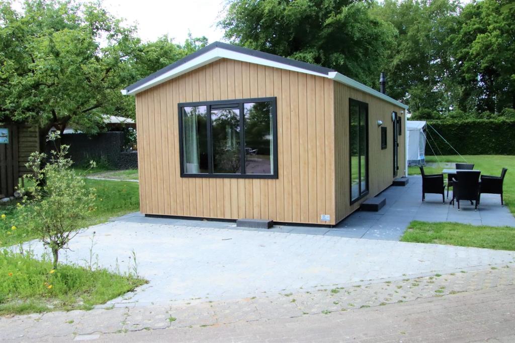 a tiny house with a patio in a yard at Chalet Merel in Drijber