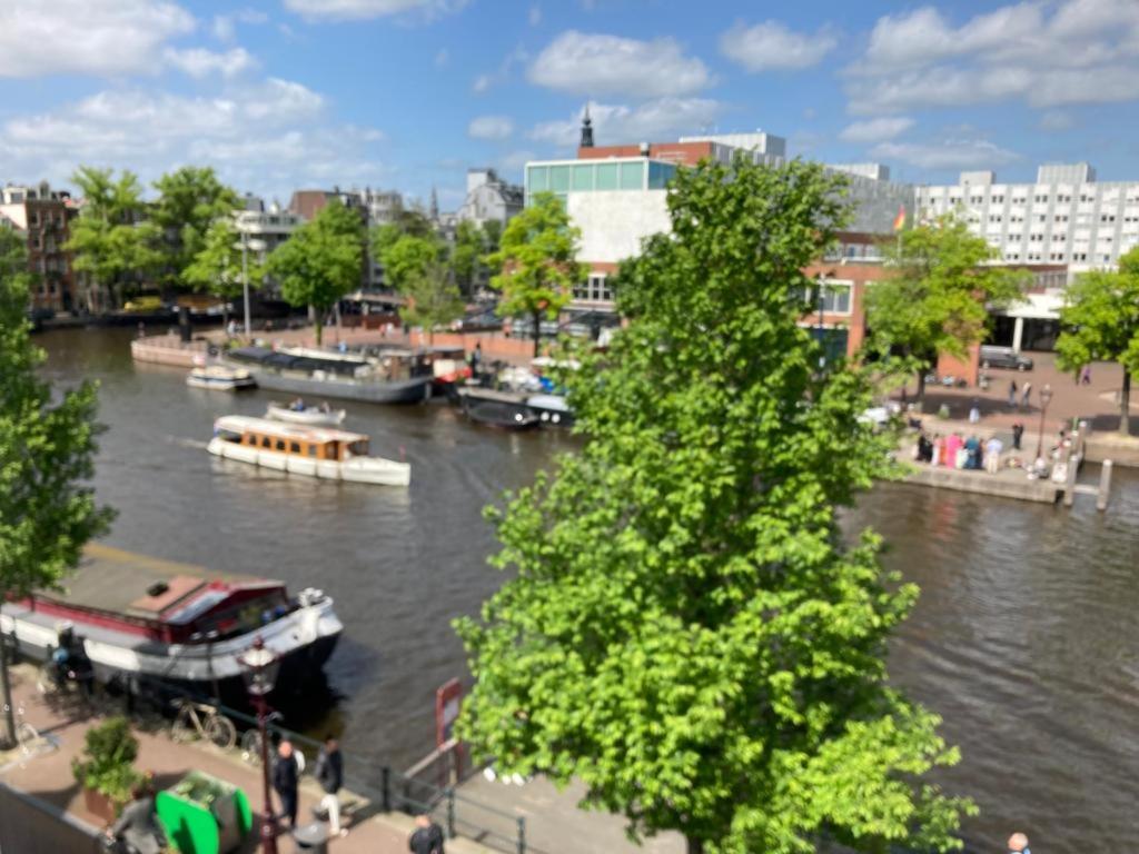 a boat on a river with boats in a city at Petite city center loft on Amstel river in Amsterdam