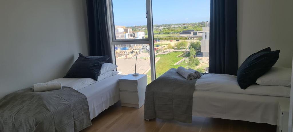 two beds in a room with a large window at Modern Spacious 3 Bedroom Apartment With Balcony At Richard Mortensens Vej Close To The Royal Arena And Fields in Copenhagen