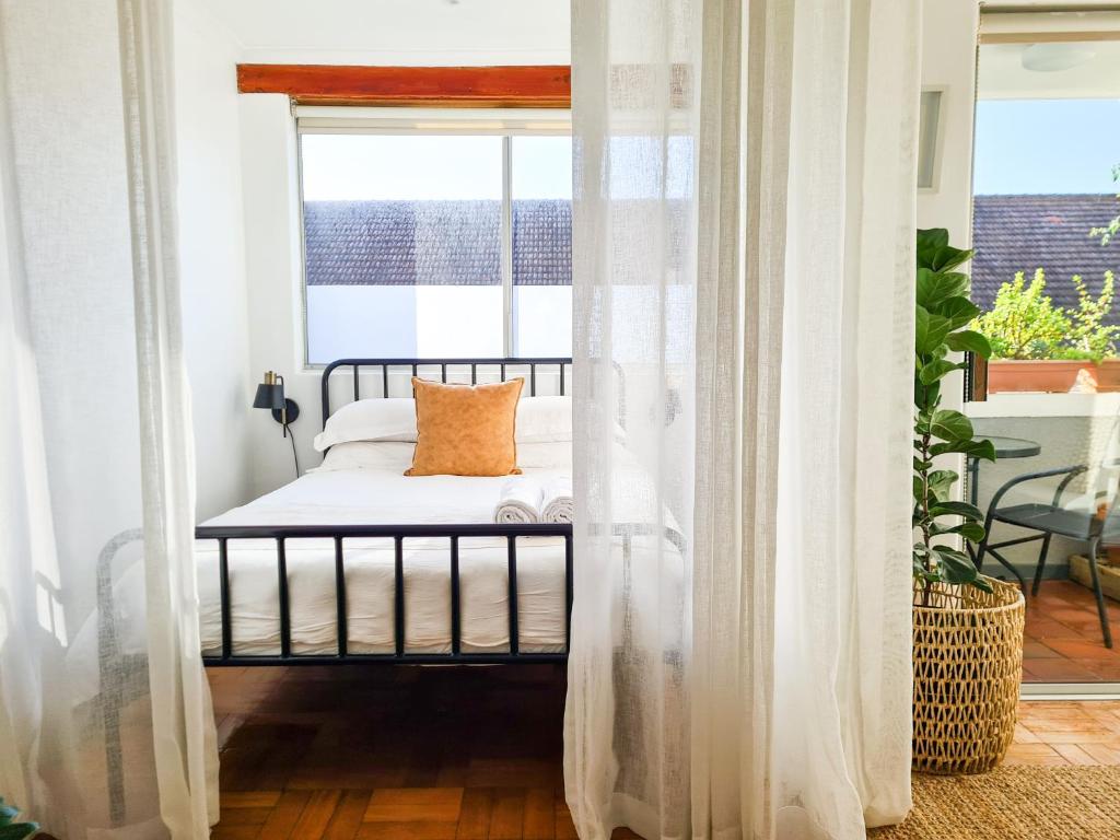 1 dormitorio con 1 cama con cortinas blancas y ventana en 13 Middelhof, en Ciudad del Cabo