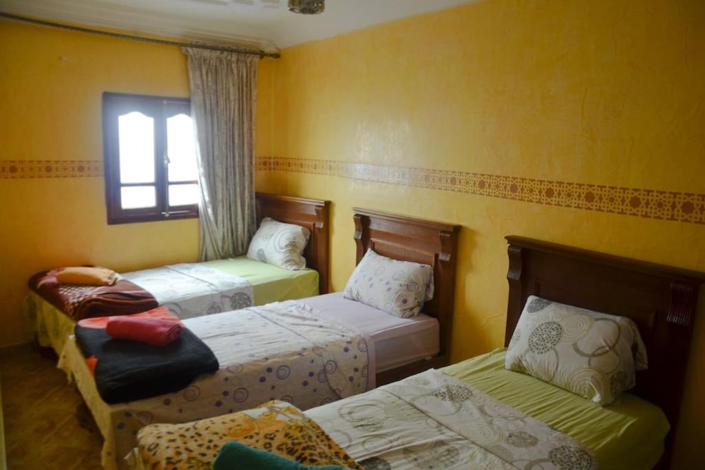 een kamer met 3 bedden en een raam bij Private appartement in the centre of Taghazout in Taghazout