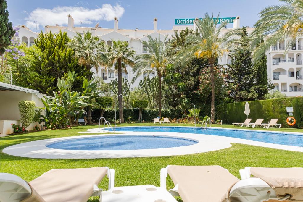 una piscina con sillas y un hotel en el fondo en Puerto Banús, Edificio Tembo, 2 bedroom apartment, parking and pool, en Marbella
