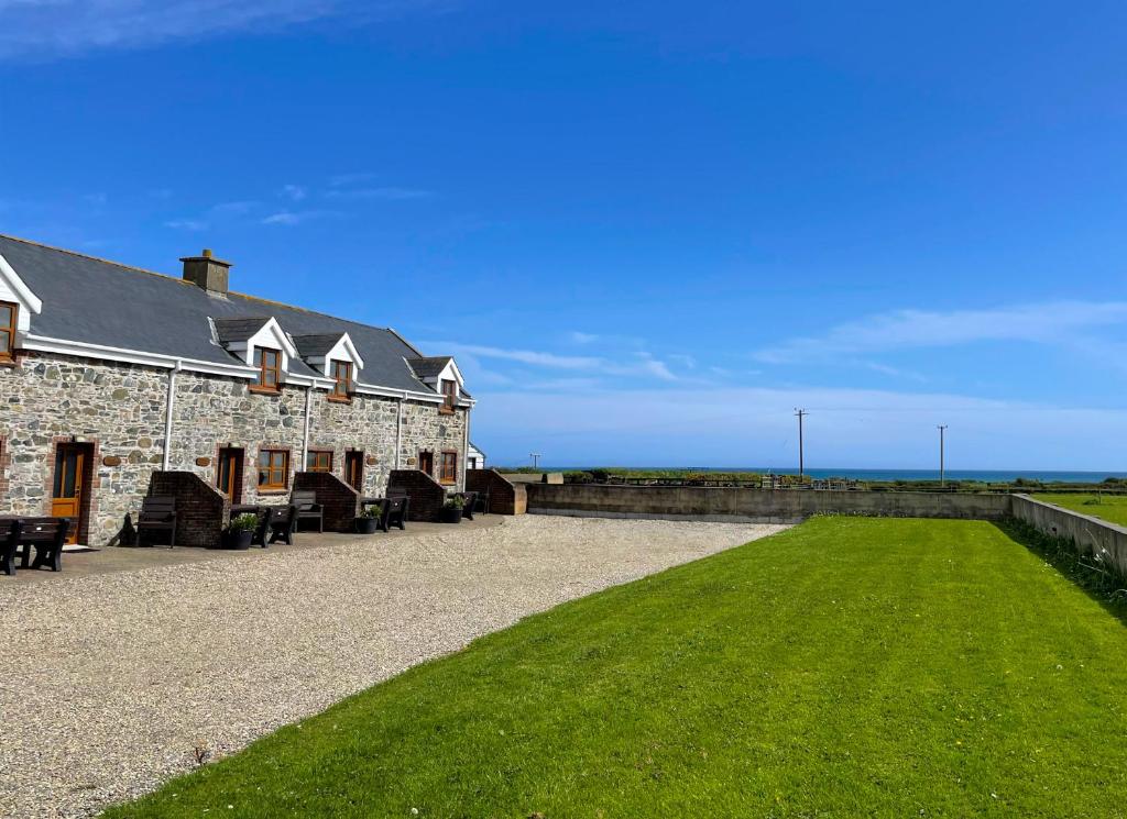 un gran edificio de piedra con un campo de césped al lado en Coninbeg Holiday Cottage by Trident Holiday Homes en Kilmore Quay