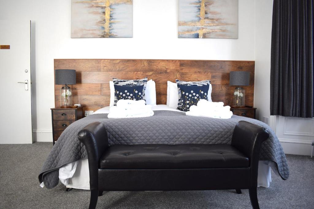um quarto com uma cama e um sofá de couro preto em Woodlyn Guest House em Gatehouse of Fleet