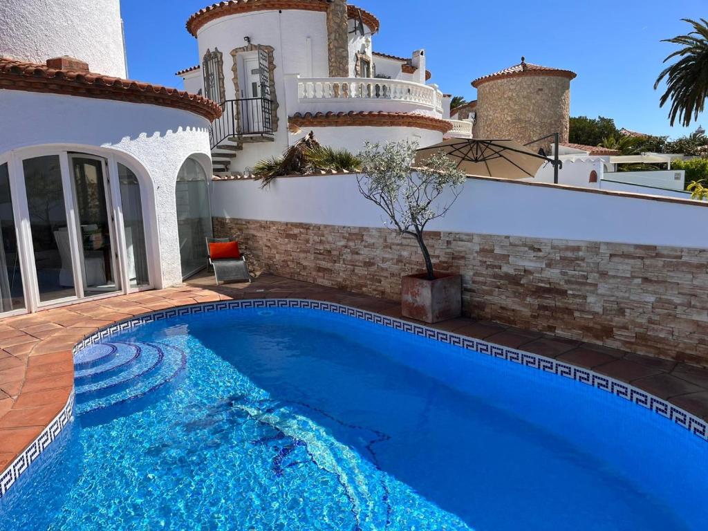 a swimming pool in front of a house at Villa Empuriabrava on main canal with 13 m private mooring, private pool, air con in all rooms, non-smoking in Empuriabrava