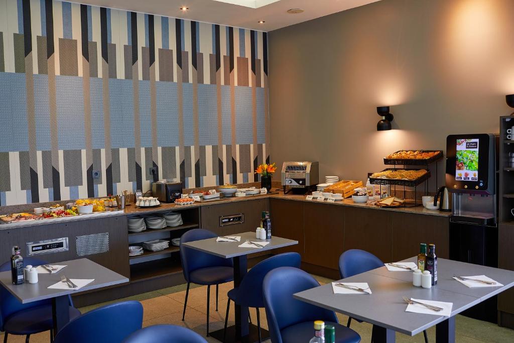 a restaurant with tables and blue chairs and a counter at Royal Antibes - Luxury Hotel, Résidence, Beach & Spa in Antibes