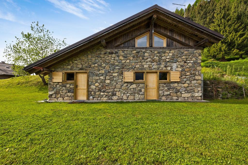 een stenen huis met een grasveld ervoor bij Baita Faé in Roncone