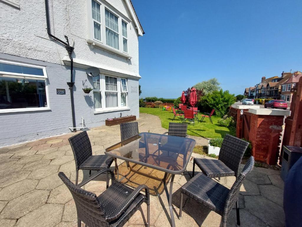 a patio with a glass table and chairs at Westbrook Lodge Guest House in Margate