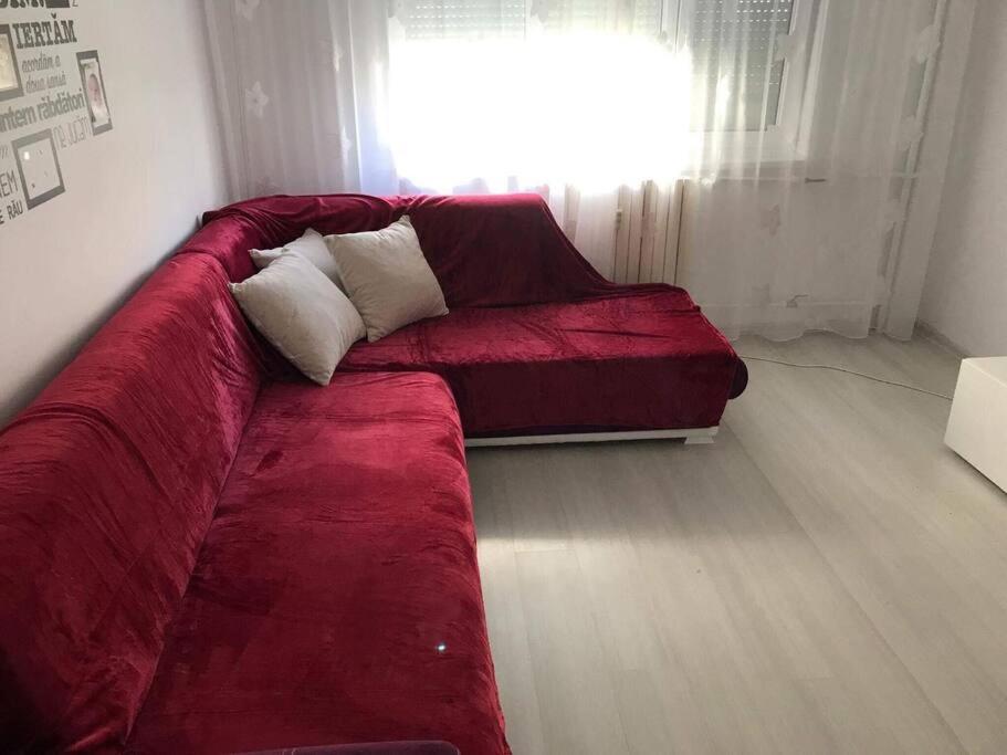 a red couch in a living room with a window at Locatie buna la 2-3 min de plaja in Mangalia