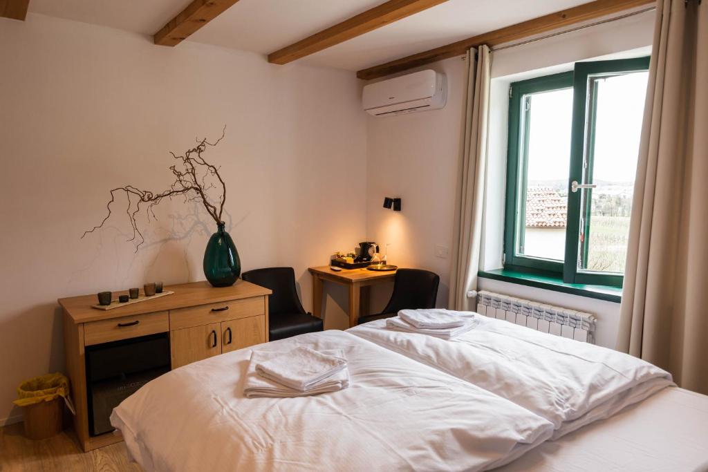 um quarto com uma cama, uma secretária e uma janela em Rooms&Vinery Bregovi - Sobe in vinska klet Bregovi em Dobravlje