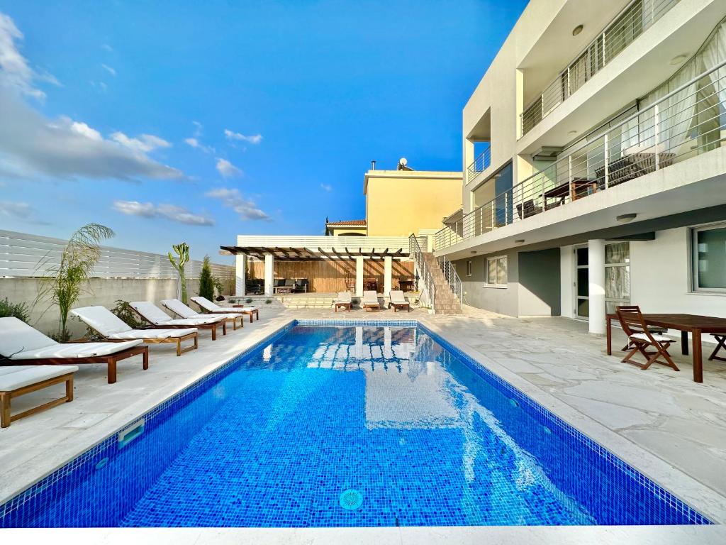 a swimming pool with lounge chairs next to a building at Amazing Luxury Villa Larnaca in Aradhippou