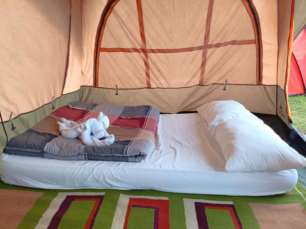 Dois ursos de peluche deitados numa cama numa tenda em Kintamani Adventure Hidden Lodge em Kintamani
