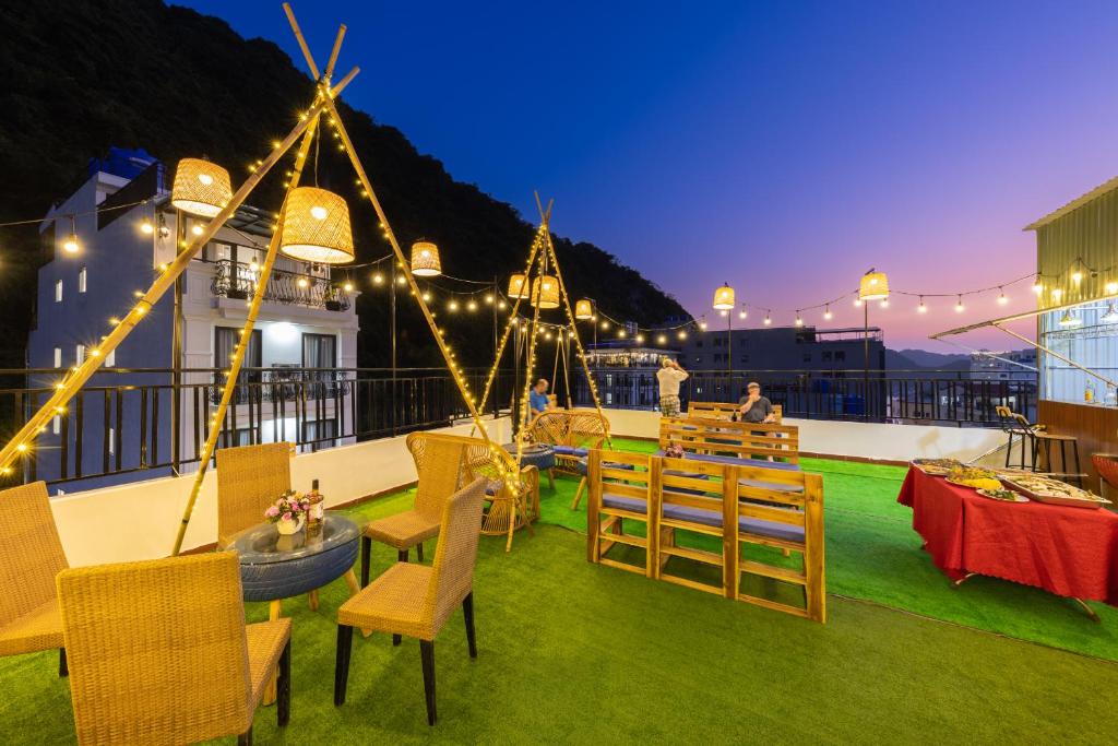 een dakterras met stoelen, tafels en verlichting bij Mountain Pearl Hotel in Cat Ba