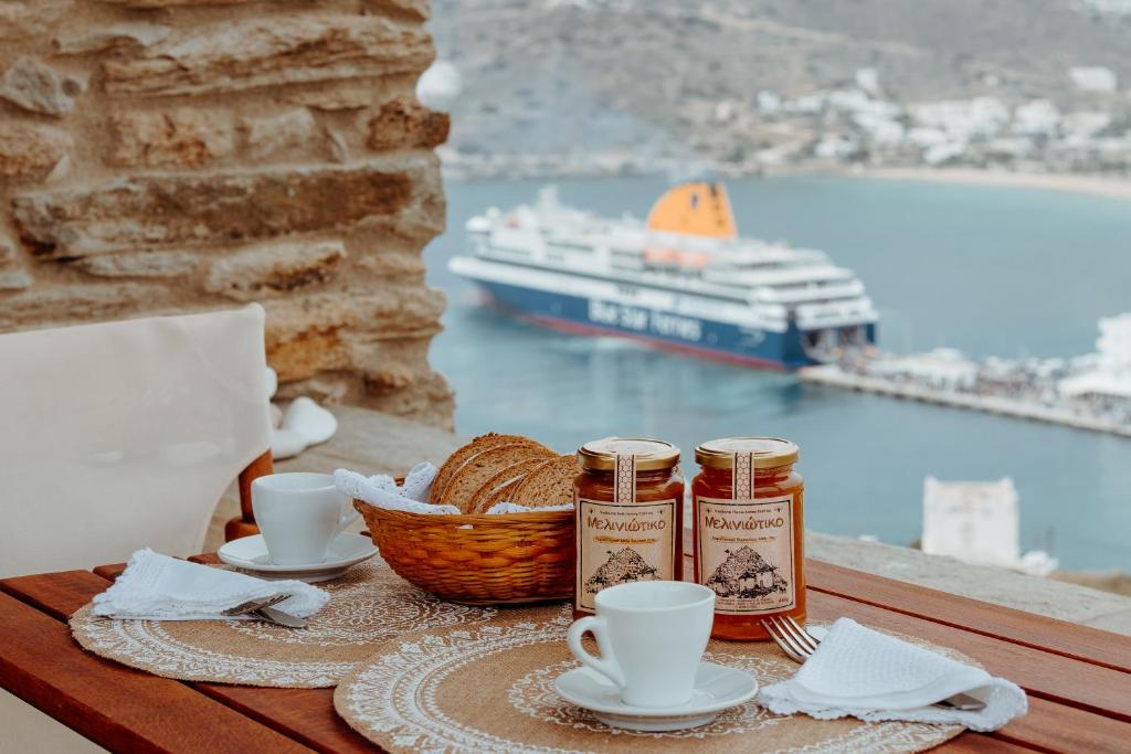 a table with a basket of bread and cups of coffee at Heliopetra Punta in Ios Chora