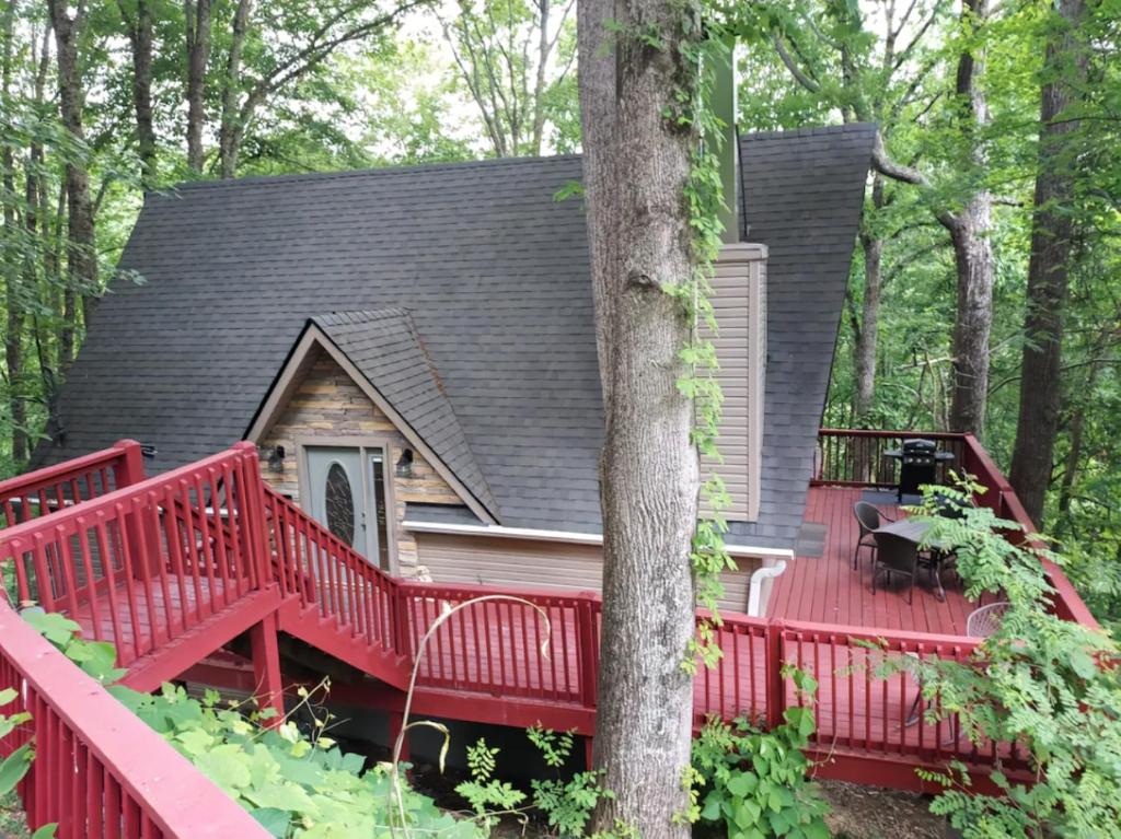 a house with a red deck in the woods at **Special Rate** Peaceful Cabin with Gameroom near Downtown Gatlinburg in Gatlinburg