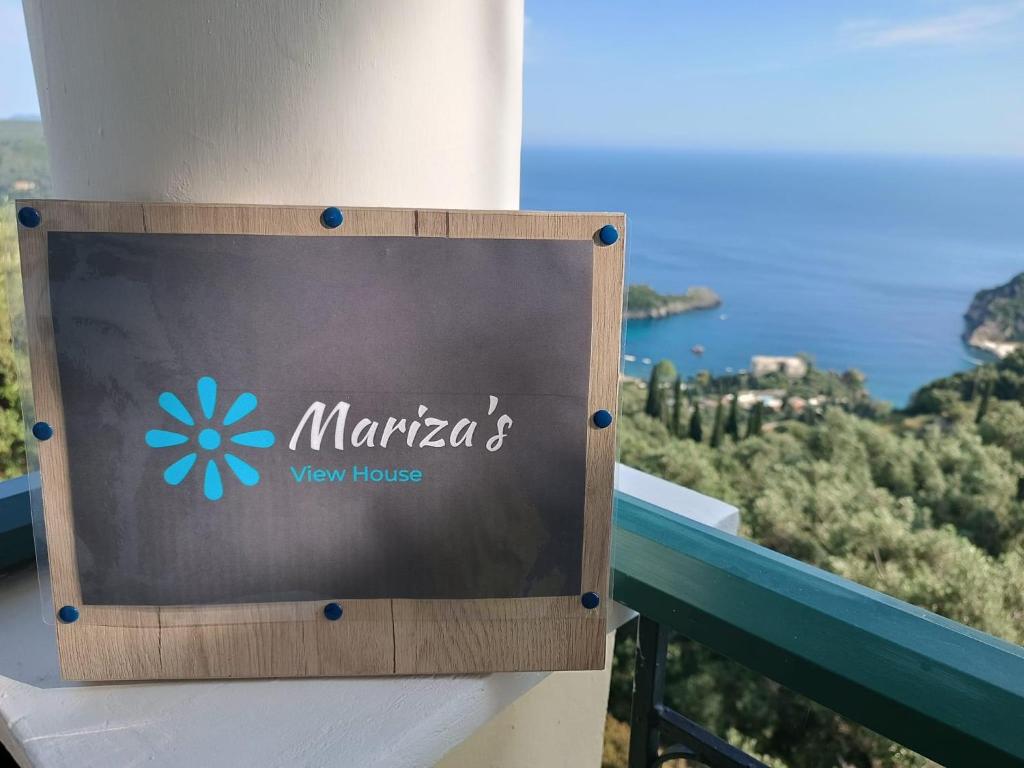 a sign on a building with a view of the ocean at Mariza's View House in Lákones