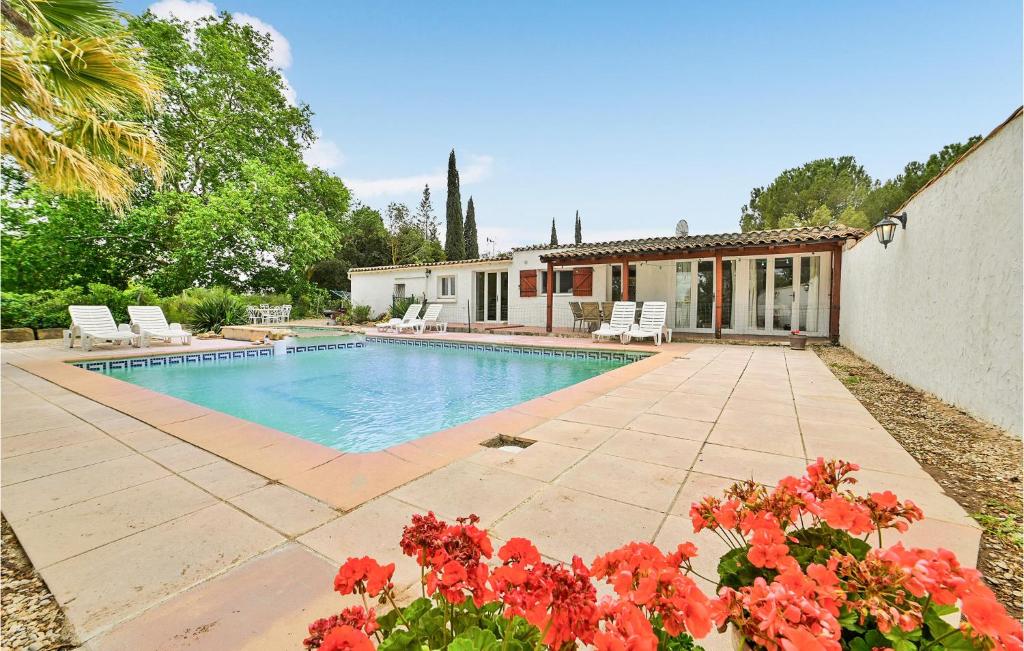 - une piscine avec des fleurs rouges en face d'une maison dans l'établissement Beautiful Home In Aspiran With 4 Bedrooms, Wifi And Private Swimming Pool, à Aspiran