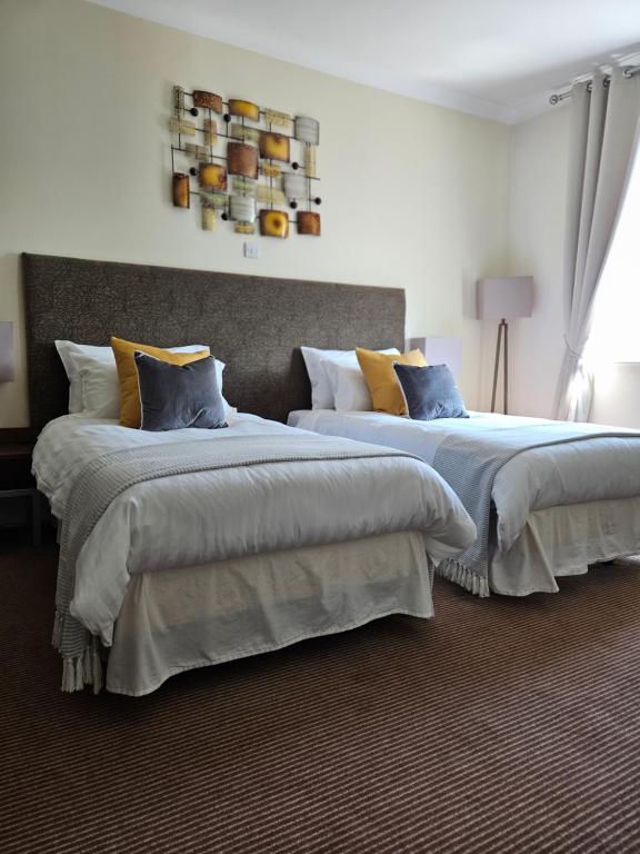 two beds in a hotel room with blue and yellow pillows at The swan at compton in Compton