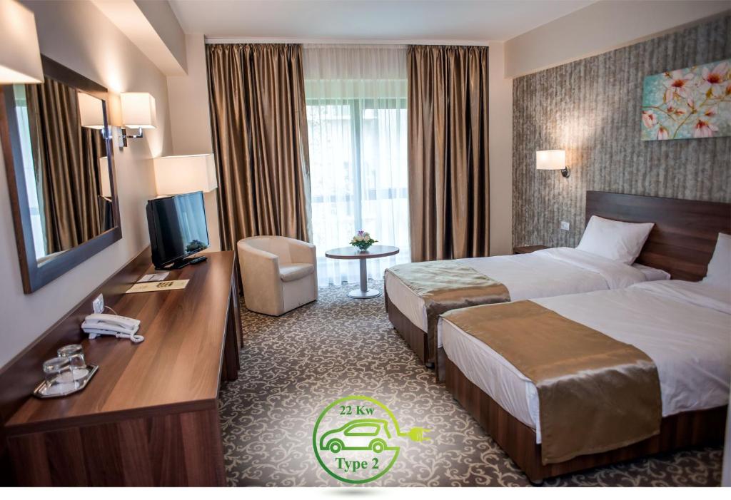Habitación de hotel con cama, escritorio y TV. en Hotel Arnia en Iaşi