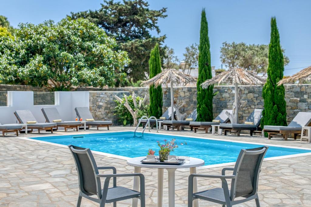 a patio with a pool and chairs and a table at Dahlia Apartments And Studios in Aliki