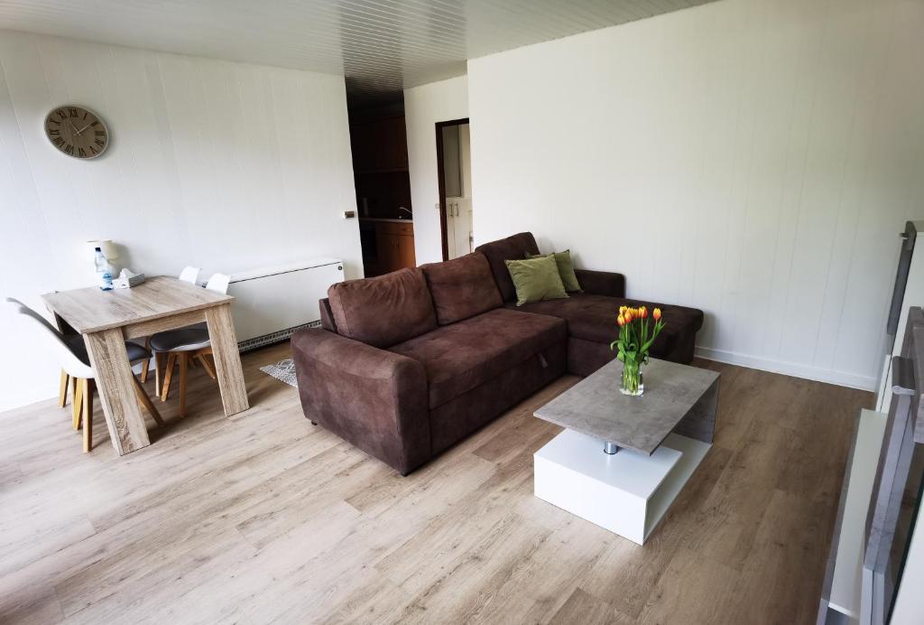 a living room with a brown couch and a table at Ferienhaus mit Sauna für romantische Zweisamkeit in Molbergen