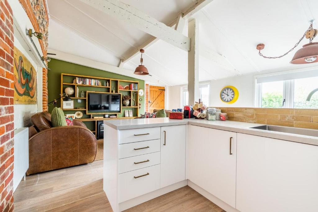 a kitchen with white cabinets and a couch in a room at Nicholson Cottage in Happisburgh
