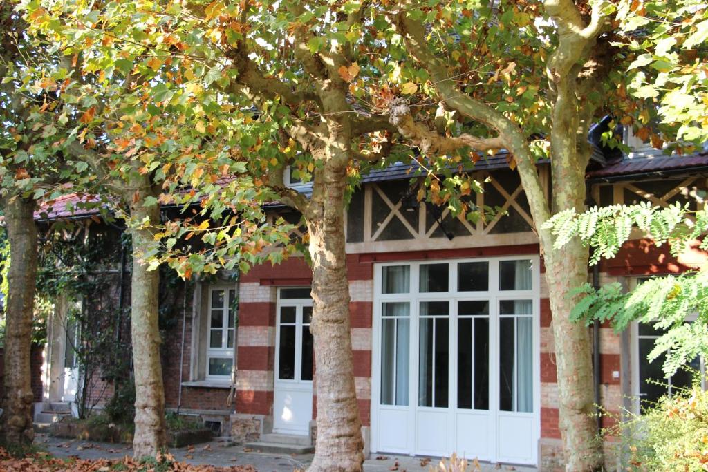 a red brick house with a white door and trees at Les Hauts du Plateau in Châtillon