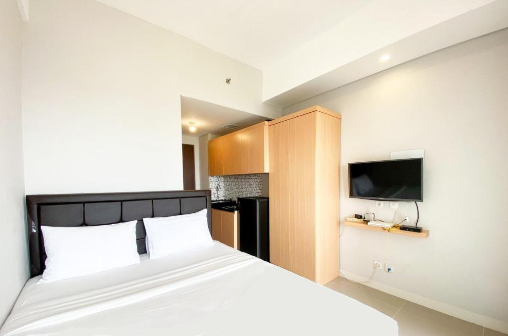 Schlafzimmer mit einem Bett und einem Flachbild-TV in der Unterkunft Apartemen Transpark Juanda Bekasi by Cheapinn in Padurenan