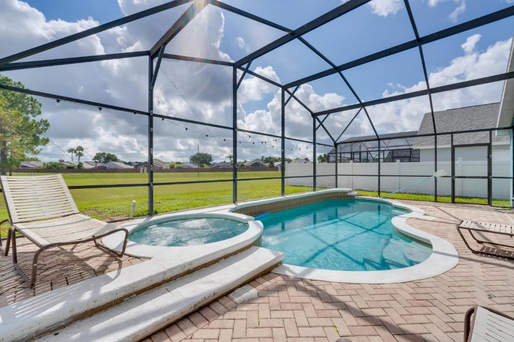 einen Pool in einem Glashaus mit einer Terrasse und einem Stuhl in der Unterkunft Kissimmee Vacation Home Heated Pool, Near Disney! in Kissimmee