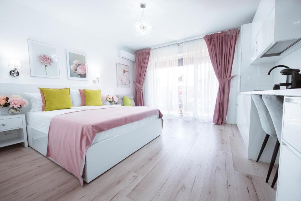 a white bedroom with a bed with pink and yellow pillows at Studio Vladut in Saturn