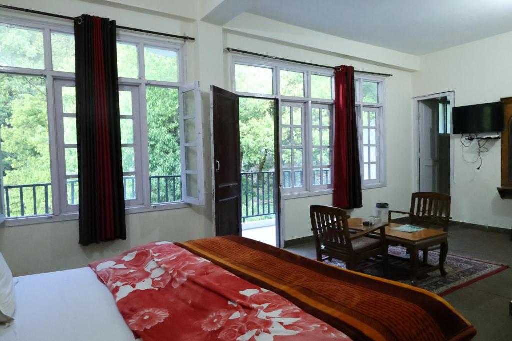 a bedroom with a bed and a table and windows at Paradise Guest House Dalhousie- Near Panchpula Water Fall in Dalhousie