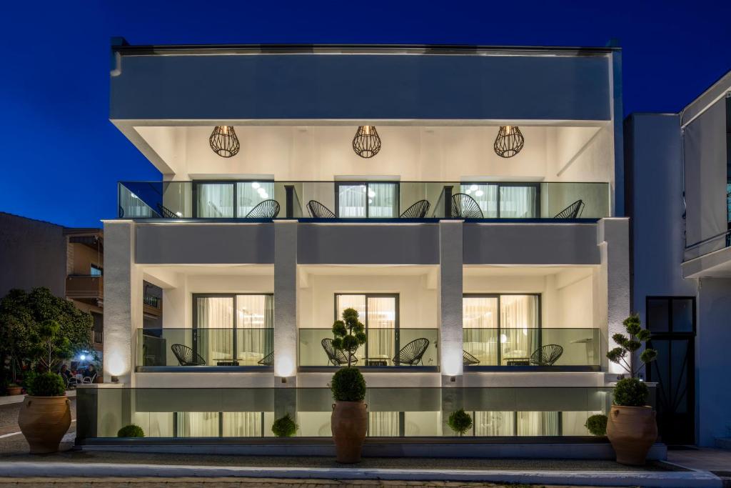 un edificio blanco con balcones por la noche en Alexandrion Appartements Down Town, en Sarti