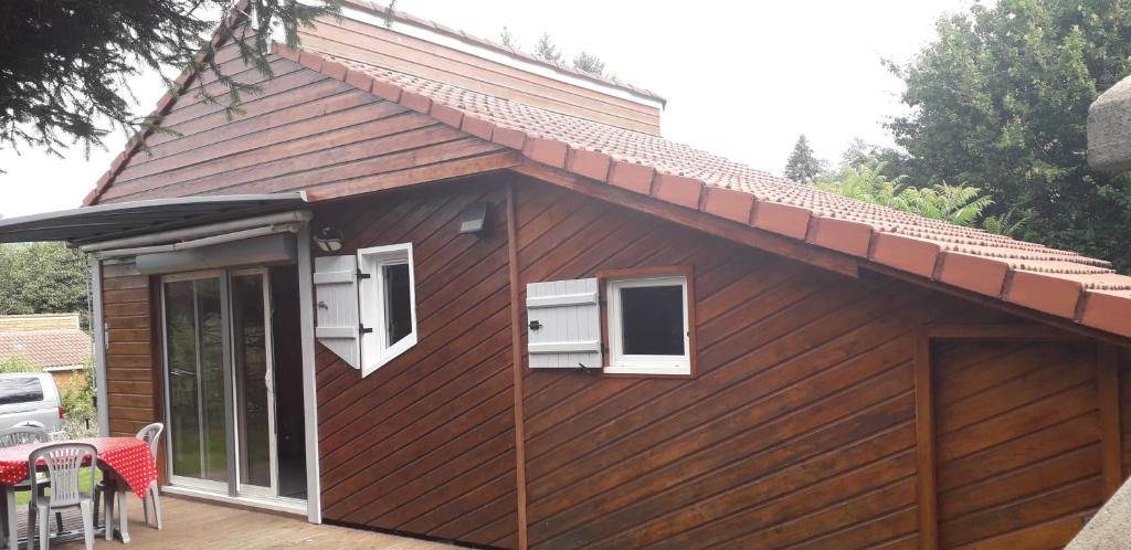 a brown house with two windows and a patio at Charmant chalet en Auvergne proche du lac in Saint-Rémy-sur-Durolle