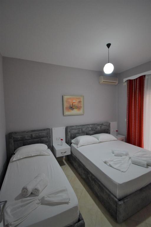 a bedroom with two beds and a red curtain at Little Cozy Apartment 1 in Sarandë