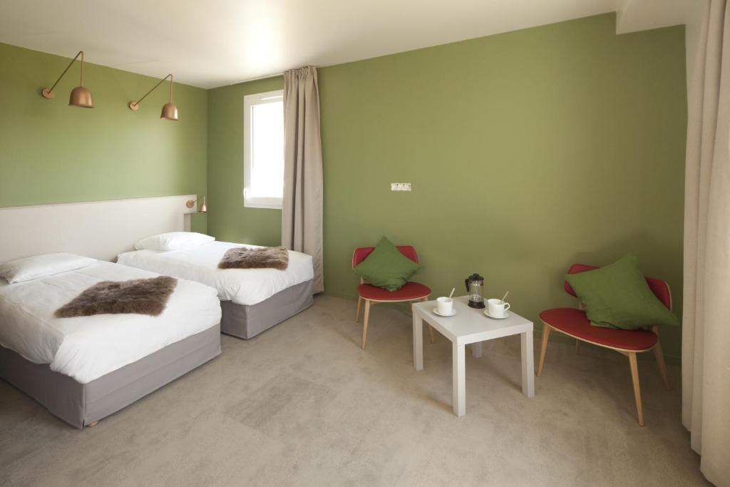 1 dormitorio con 2 camas, mesa y sillas en Les Clefs du Roy by Popinns, en Buc