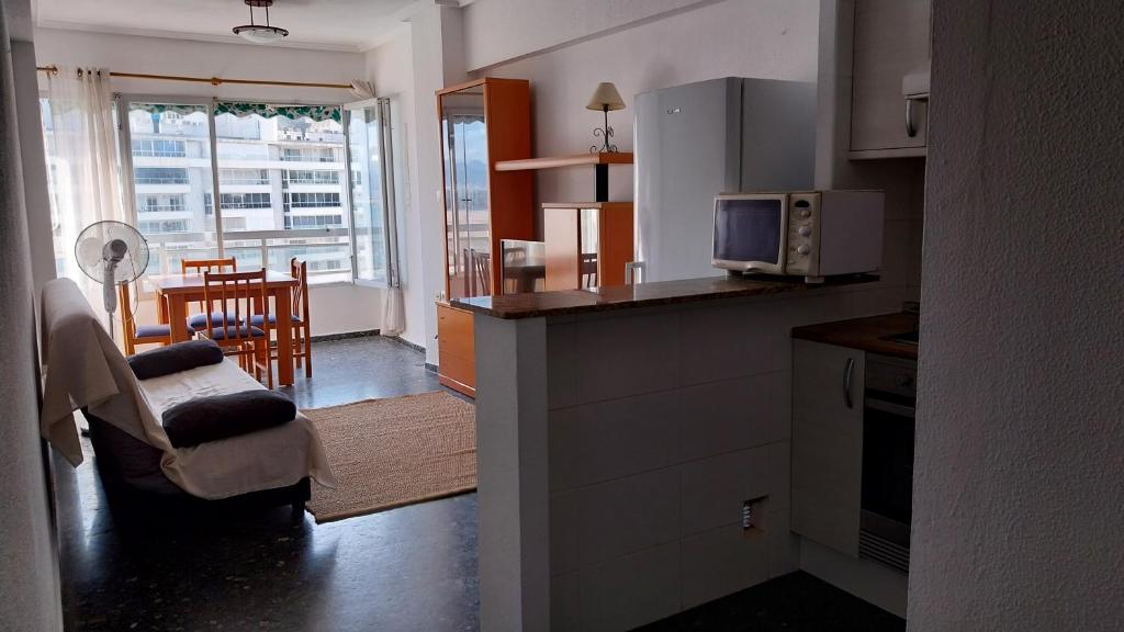 eine Küche und ein Wohnzimmer mit einer Mikrowelle und einem Tisch in der Unterkunft Apartamento pequeño frente al mar con piscina in Cullera