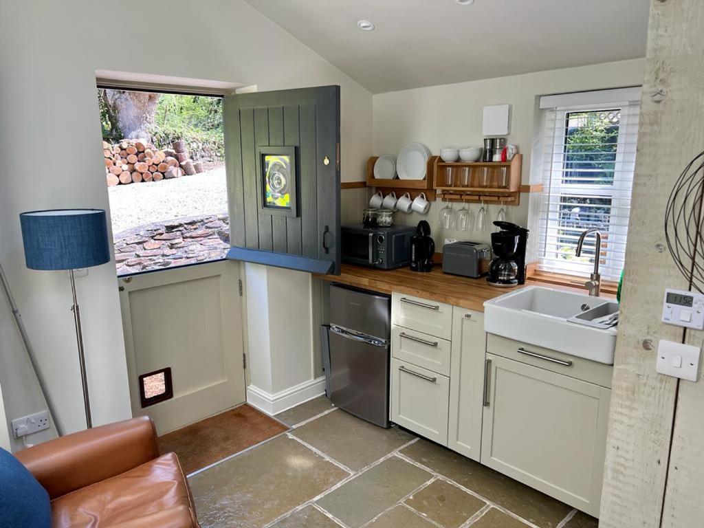uma cozinha com armários brancos e um lavatório em The Leat at The Old Mill em Tavistock