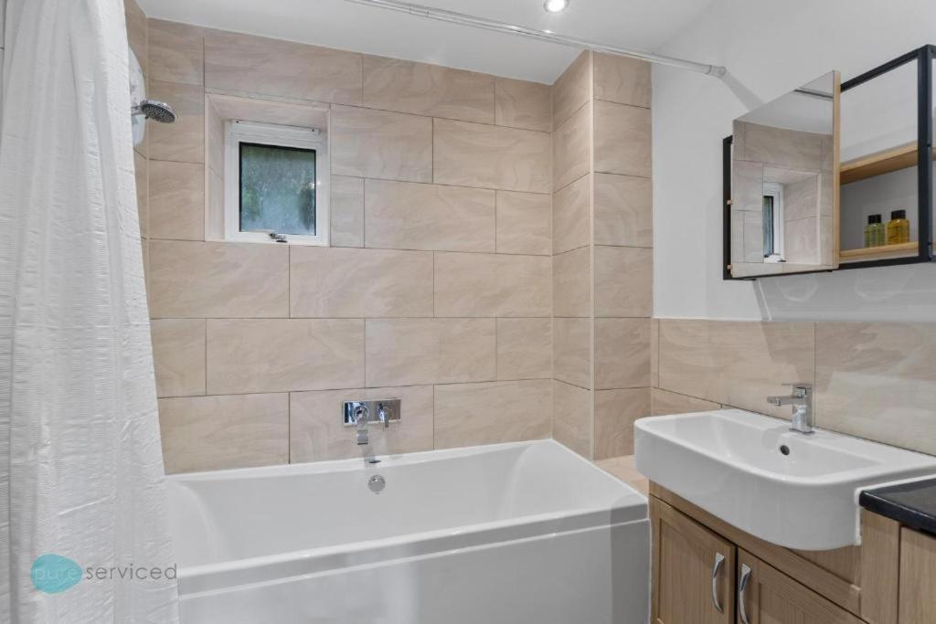 a bathroom with a white tub and a sink at 4 Bed- Trematon By Pureserviced in Plymouth
