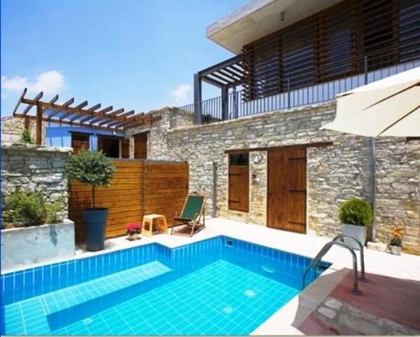 a swimming pool in front of a house with an umbrella at RedBlue Door Two Traditional Listed Houses in Pano Lefkara