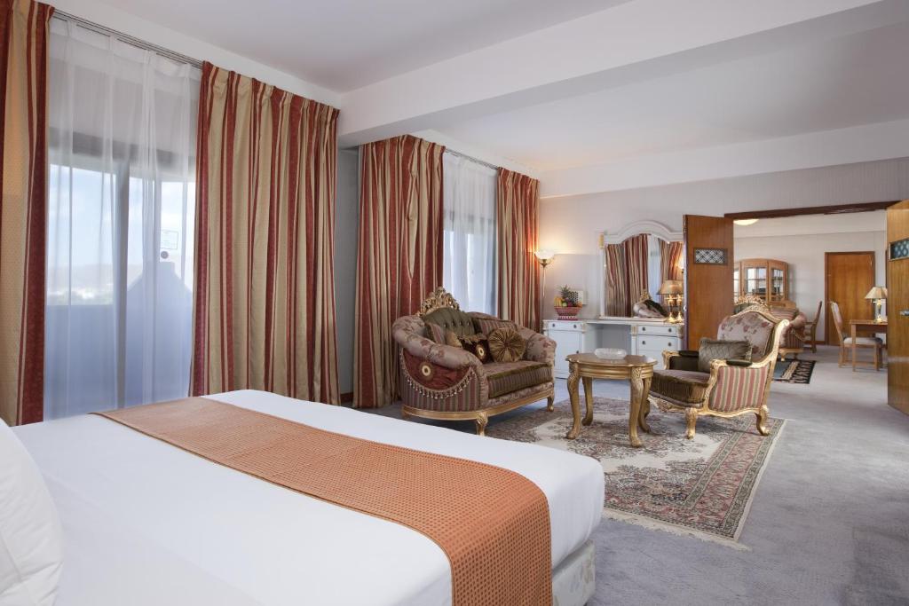 Habitación de hotel con cama y sala de estar. en Gloria Inn Najran, en Najrán