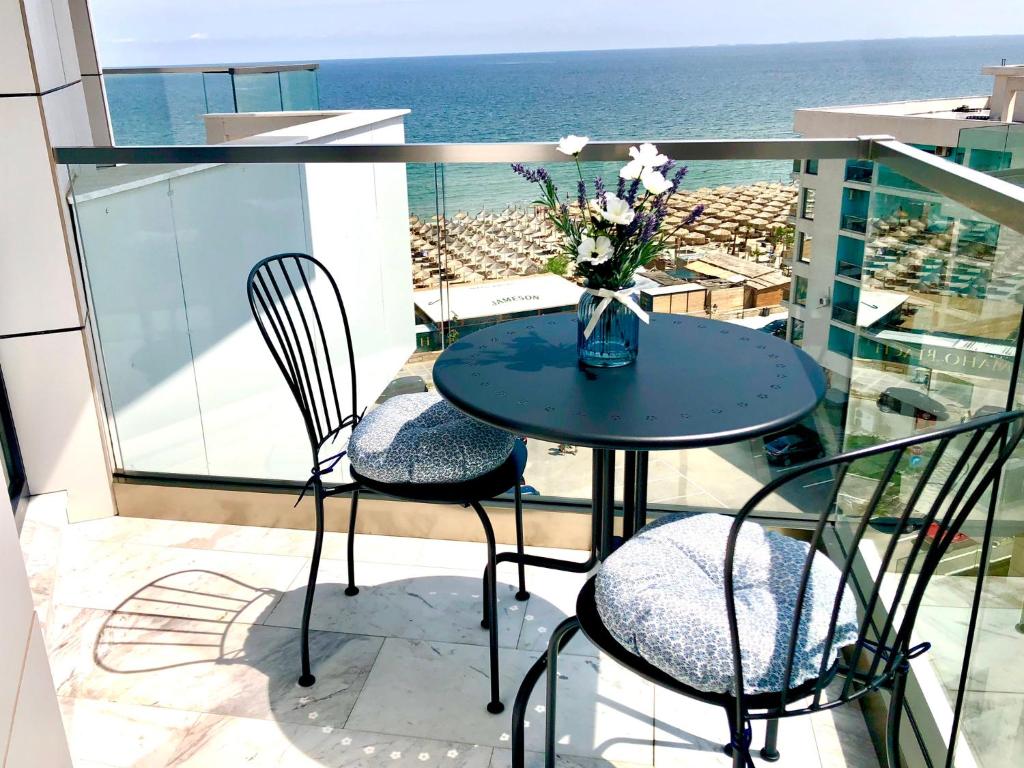 a table with chairs and a vase of flowers on a balcony at Veli Apartments 348 Infinity in Mamaia Sat/Năvodari