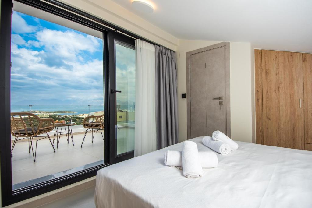 a bedroom with a bed with a view of a balcony at Agro Nostro-Agave with superb view in Agios Nikolaos