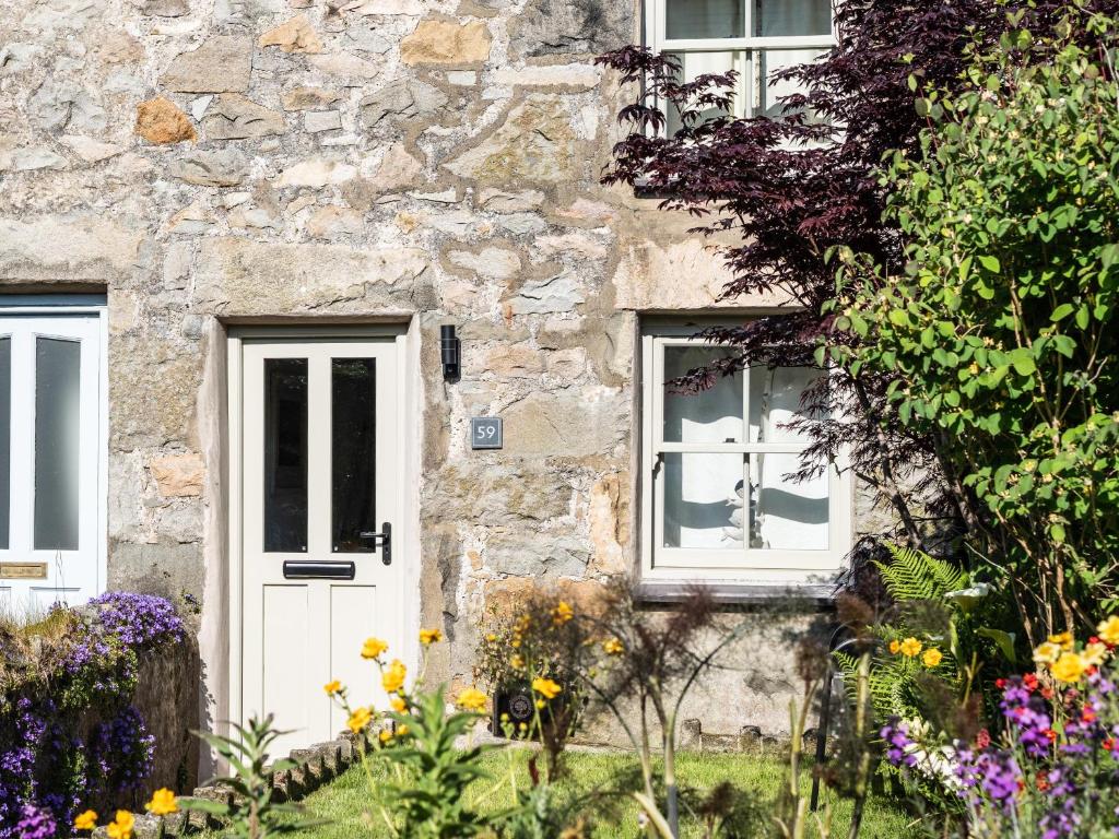 a stone house with a white door and windows at Ynata in Caernarfon