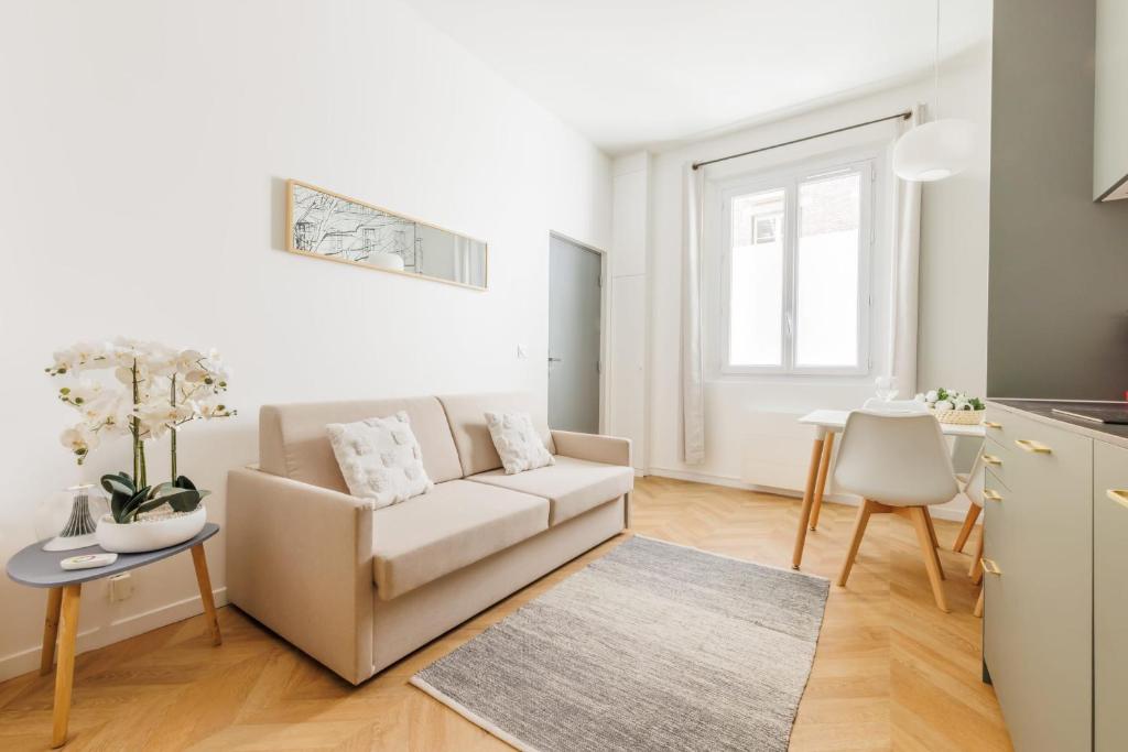 un salon blanc avec un canapé et une table dans l'établissement Appartement Moderne 1BR-4P - Guy Moquet, à Paris